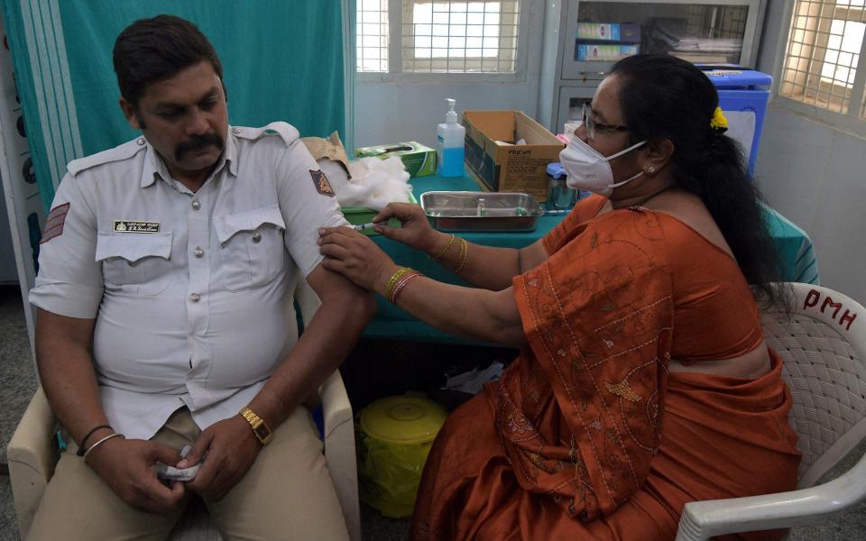 A medical worker inoculates a traffic policeman with a Covid-19 coronavirus vaccine at a hospital in Bangalore - MANJUNATH KIRAN/AFP