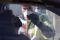 Cody Tupen, a firefighter with the Puget Sound Regional Fire Authority, performs a deep nasal nose-swab COVID-19 test on Nancy Backus, left, the mayor of Auburn, Wash., at a King County COVID-19 testing site in Auburn, south of Seattle, Wednesday, Oct. 28, 2020. State health officials say that a new COVID-19 report released Wednesday shows an increase in coronavirus cases and hospitalizations throughout Washington state, and if not brought under control, officials said the spike could jeopardize progress toward reopening schools, strain the health care system and increase risks during the holiday season. (AP Photo/Ted S. Warren)