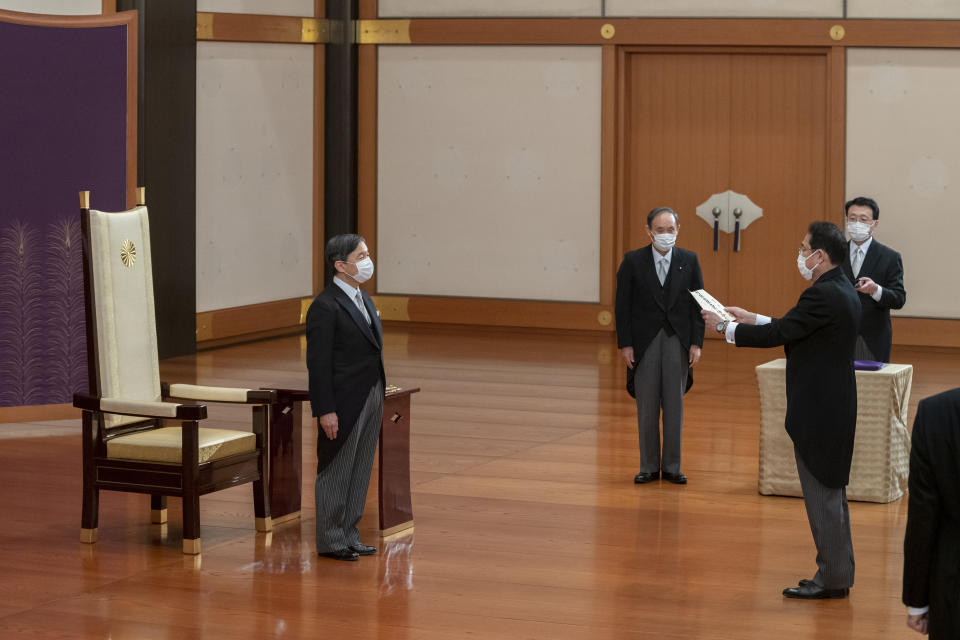In this photo provided by the Imperial Household Agency of Japan, Japan's Emperor Naruhito, left, stands before new Prime Minister Fumio Kishida, as former prime minister Yoshihide Suga looks on during Kishida's attestation ceremony at the Imperial Palace in Tokyo, Monday, Oct. 4, 2021. (Imperial Household Agency of Japan via AP)