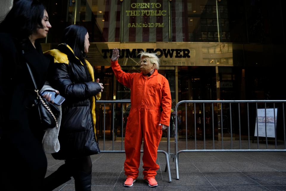 Mike Hisey, left, dressed to portray former President Donald Trump in a prison uniform, stands in front of the barricaded Trump Tower.