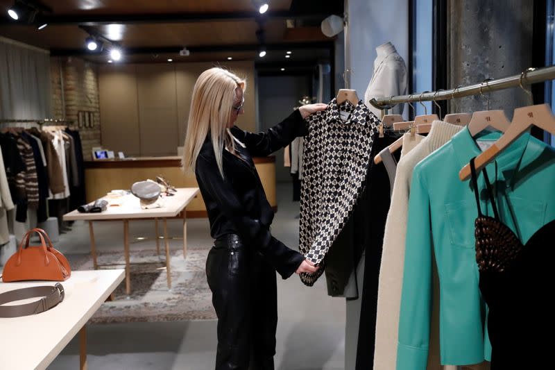 A shop assistant looks clothes by the Hungarian luxury brand Nanushka are seen in the Nanushka store in Budapest