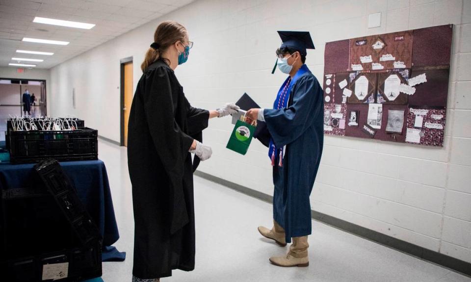 Guidance counselor Cara Shaw hands a gift bag to graduate Jahleel Cruz after he received his diploma at Southeast Raleigh High School’s socially distanced graduation ceremony on Wednesday, May 27, 2020.