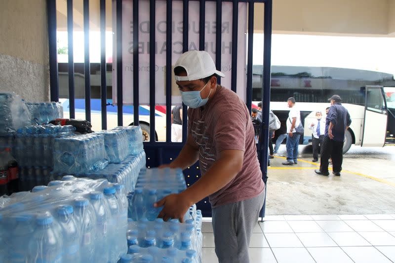 A hotel employee arranges bottled water at the entrance of a school, which will be used as a temporary shelter for tourists, in preparation for the arrival of Hurricane Delta, in Cancun
