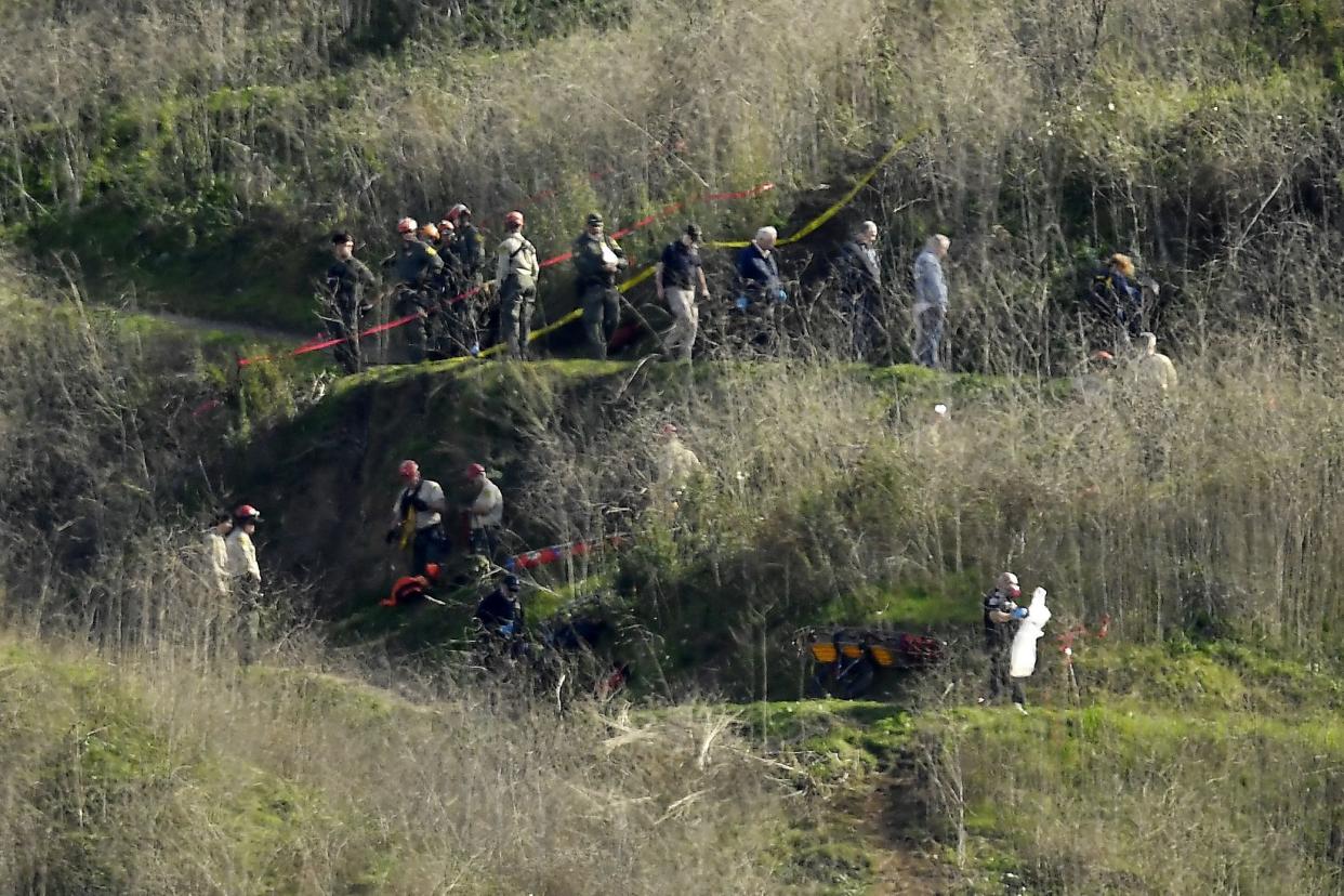 Investigators work the scene of a helicopter crash that killed former NBA basketball player Kobe Bryant, his 13-year-old daughter, Gianna, and several others Monday, Jan. 27, 2020, in Calabasas, Calif. Los Angeles County has to pay $2.5 million to two families who lost relatives in the fatal helicopter crash. The Board of Supervisors on Tuesday, Nov. 2, 2021, approved a settlement of two federal lawsuits filed by the Altobelli and Mauser families alleging they suffered emotional distress over graphic photographs of the scene that reportedly were taken or shared by Los Angeles County sheriff's deputies and firefighters.