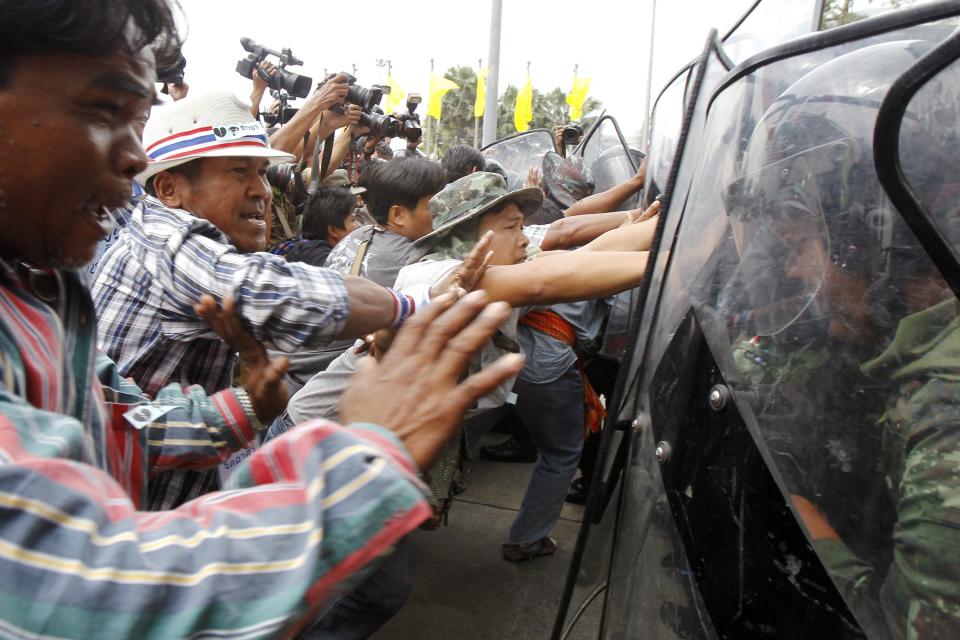 Farmers push against the shields of soldiers guarding the temporary office of Thai PM Yingluck during a protest in Bangkok