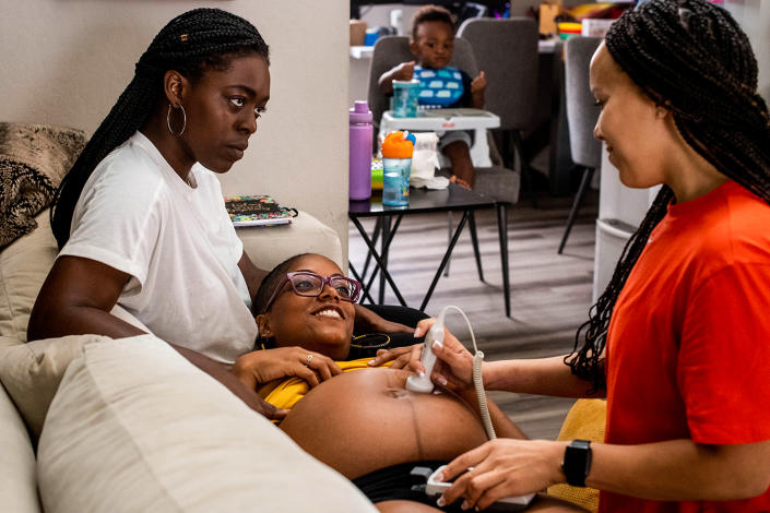 Image: Midwife Angie Miller, right, listens to the heart beat of MyLin Stokes Kennedys baby, center, with her wife Lindsay and their child Lennox, 21 months, in California on June 29, 2021. Black women are turning to midwives to avoid racism , Mortality rates and unnecessary C-sections in the hospitals.  (Sarah Reingewirtz/MediaNews Group via Getty Images)