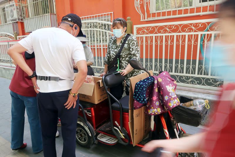 Street vendor Shan Peng attends to customers at her food stall set up on an electric tricycle outside a residential compound in Beijing