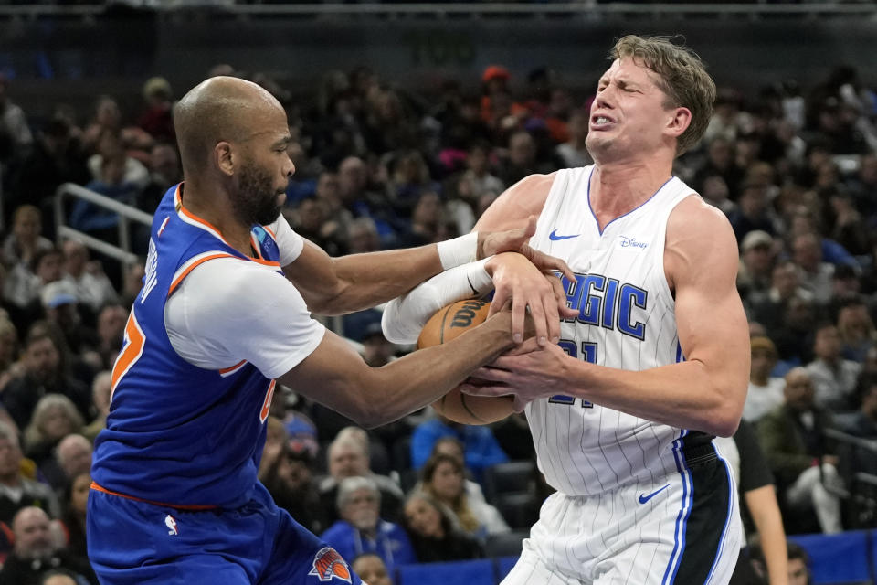 New York Knicks forward Taj Gibson, left, tries to strip the ball from Orlando Magic center Moritz Wagner during the second half of an NBA basketball game, Friday, Dec. 29, 2023, in Orlando, Fla. (AP Photo/John Raoux)