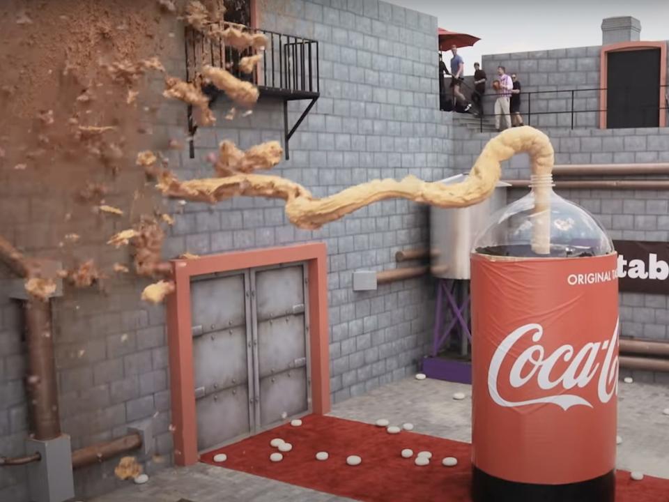 A screenshot showing brown foam shooting out of the large bottle onto a wall.