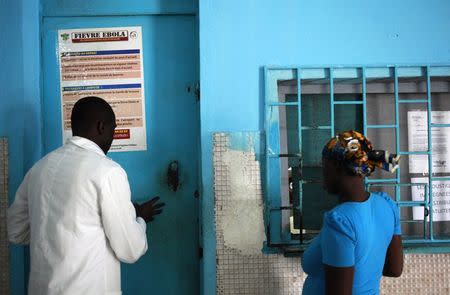 A woman stands at a pharmacy next to a poster displaying a government message against Ebola, at a maternity hospital in Abidjan August 14, 2014. REUTERS/Luc Gnago