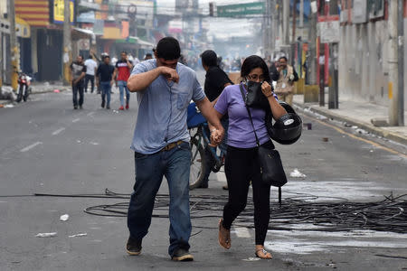 People overcome by tear gas walk away from clashes between supporters of Salvador Nasralla, presidential candidate for the Opposition Alliance Against the Dictatorship, and police during a protest caused by the delayed vote count for the presidential election in San Pedro Sula, Honduras December 1, 2017. REUTERS/Moises Ayala