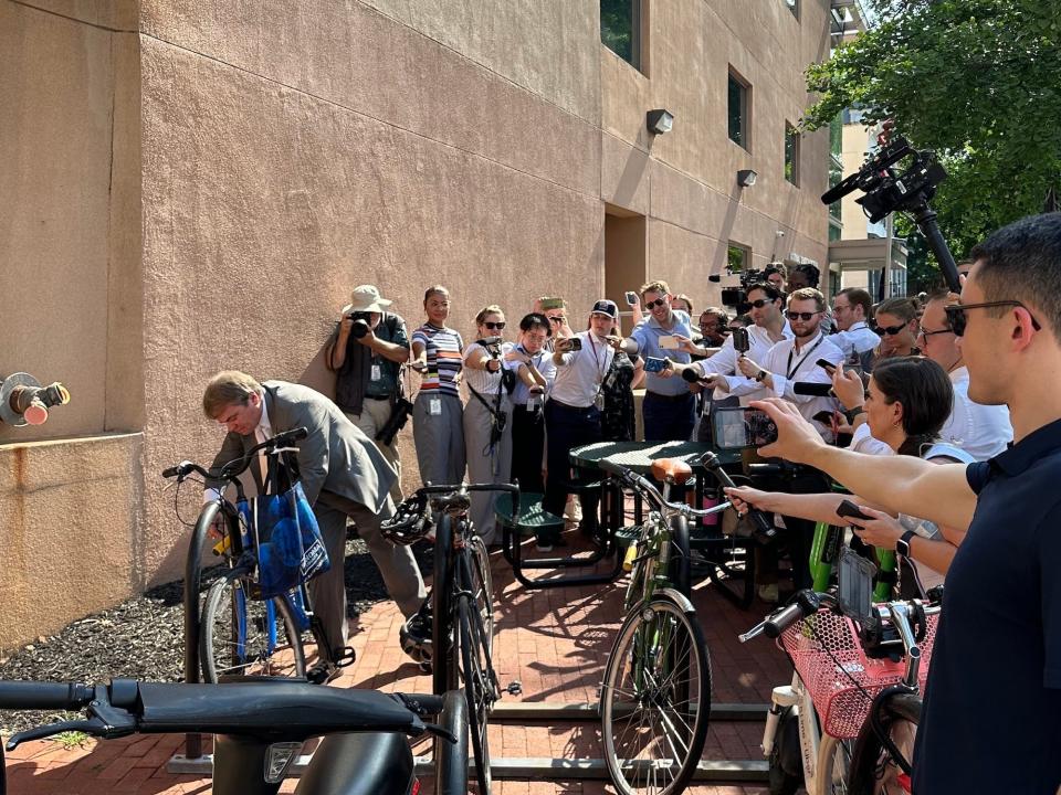 Rep. Mike Quigley fields questions from reporters while unlocking his bike outside the DNC.