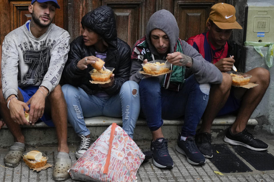 La gente come una comida caliente gratis afuera de un comedor comunitario administrado por el Movimiento de Trabajadores Excluidos (MTE) en Buenos Aires, Argentina, el miércoles 13 de marzo de 2024. (AP Foto/Natacha Pisarenko)