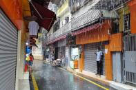 A man, wearing a face mask, shelters from the rain in Guangzhou's Xiaobei neighborhood