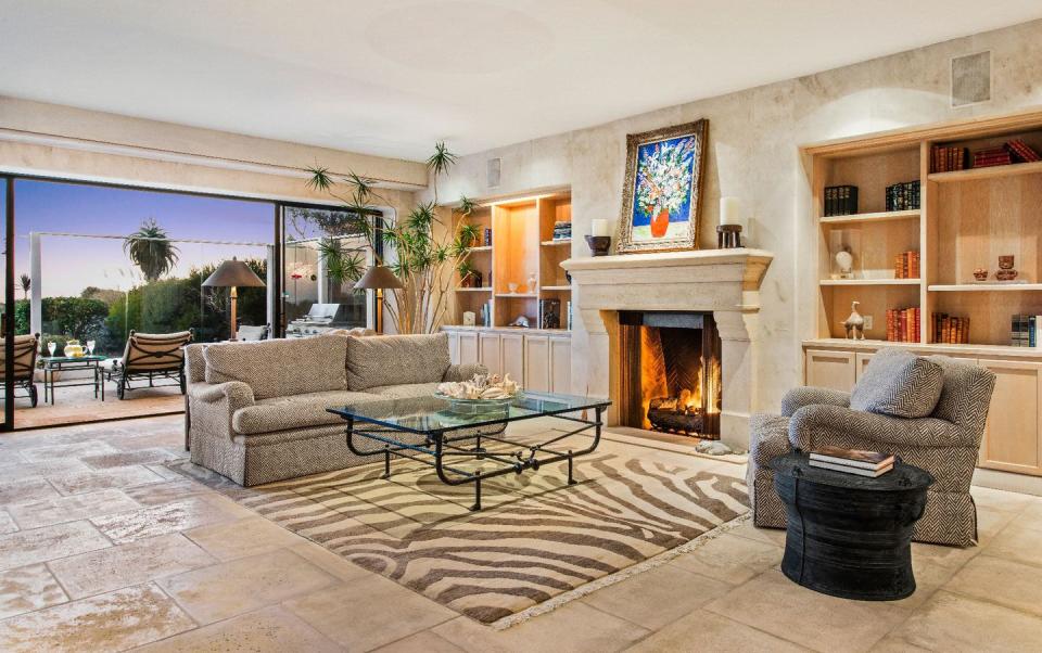 The indoor-outdoor living room has a large fireplace.