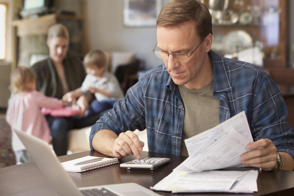 father paying bills with family behind him
