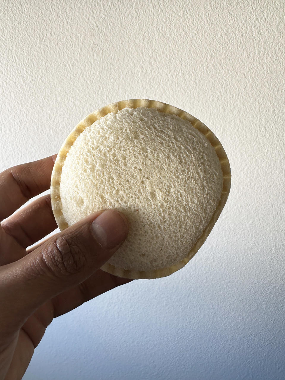 A hand holding a Smucker's Uncrustables sandwich