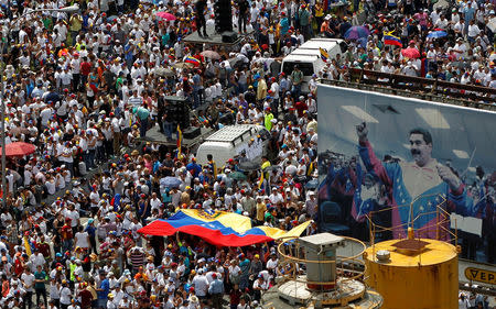 Opposition supporters take part in a rally against Venezuela's President Nicolas Maduro next to a poster of him in Caracas, Venezuela, October 26, 2016. REUTERS/Christian Veron