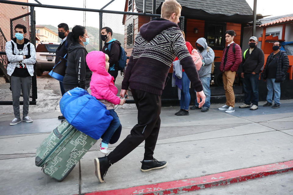 A Ukrainian man pulls a child on luggage as other people wait in line.