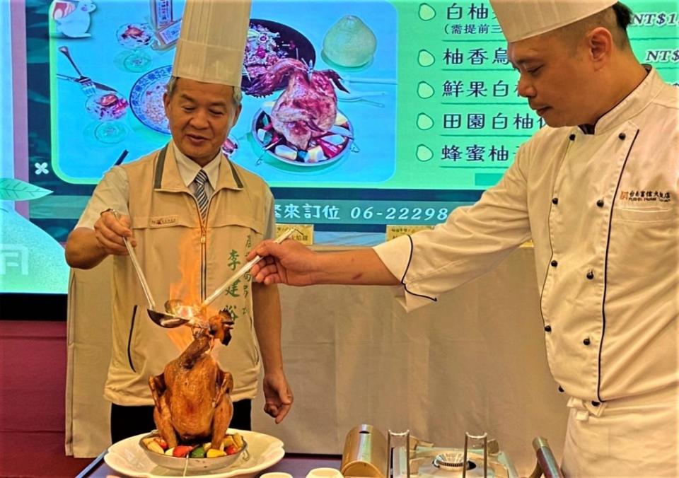 農業局長李建裕（左）及富信大飯店主廚吳俊傑表演柚香火焰雞上菜秀。（農業局提供）