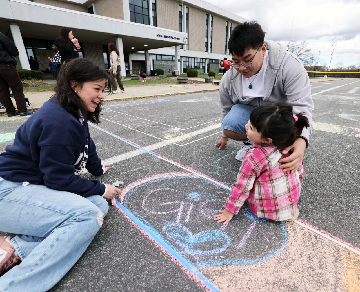 Alexa Rooney helps Nina Miranda, 2, with her artwork and brother Ayden Miranda, 16, during Brockton High School National Honor Society's "Chalk Day" on Saturday, April 13, 2024. Chalk drawings gave positive messages.