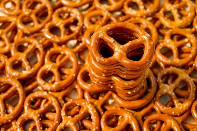 A group of bite sized pretzels, some stacked, on a table.