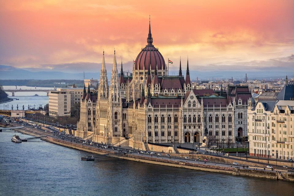 the hungarian parliament on the danube river at sunset in budapest, hungary