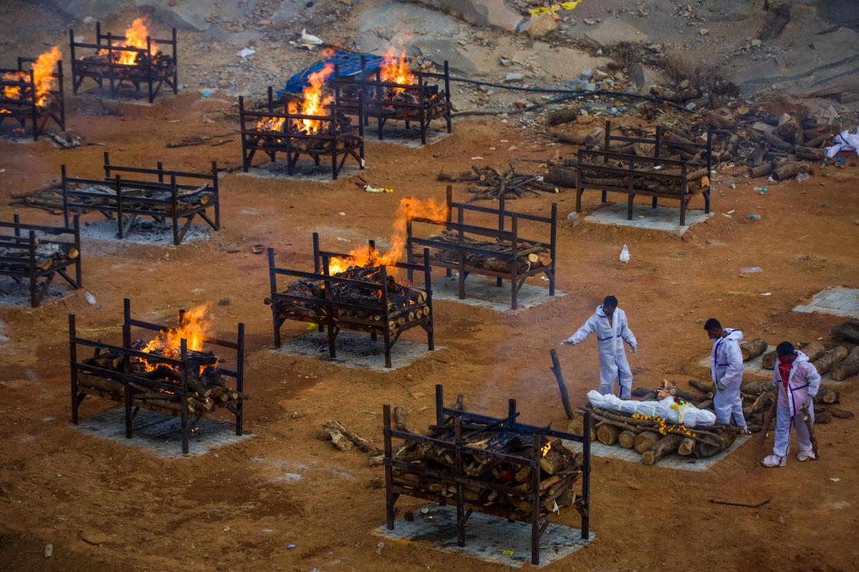 Men wearing PPE (Personal Protective Equipment) perform the last rites of a deceased relative in a disused granite quarry repurposed to cremate the dead due to COVID-19 on April 30, 2021, in Bengaluru, India.