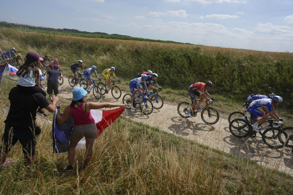 The pack with Belgium's Wout Van Aert, wearing the overall leader's yellow jersey, passes over a sector of cobblestones during the fifth stage of the Tour de France cycling race over 157 kilometers (97.6 miles) with start in Lille Metropole and finish in Arenberg Porte du Hainaut, France, Wednesday, July 6, 2022. (AP Photo/Thibault Camus)