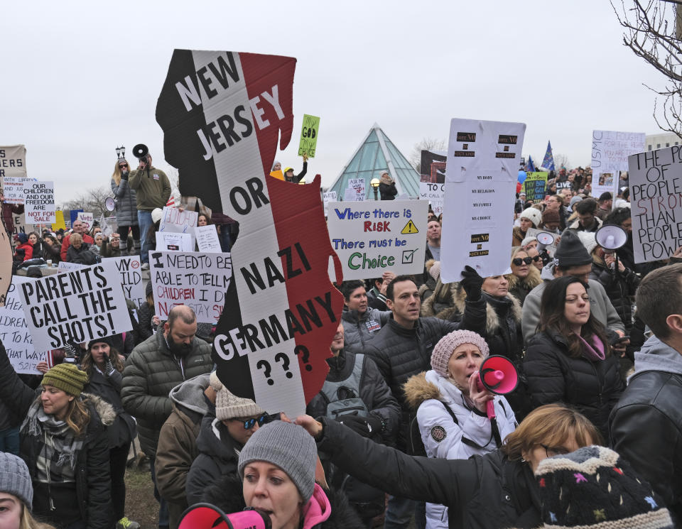 People hold signs during a protest at the state house in Trenton, N.J., Monday, Jan. 13, 2020. New Jersey lawmakers are set to vote Monday on legislation to eliminate most religious exemptions for vaccines for schoolchildren, as opponents crowd the statehouse grounds with flags and banners, including some reading "My Child, My Choice." (AP Photo/Seth Wenig)