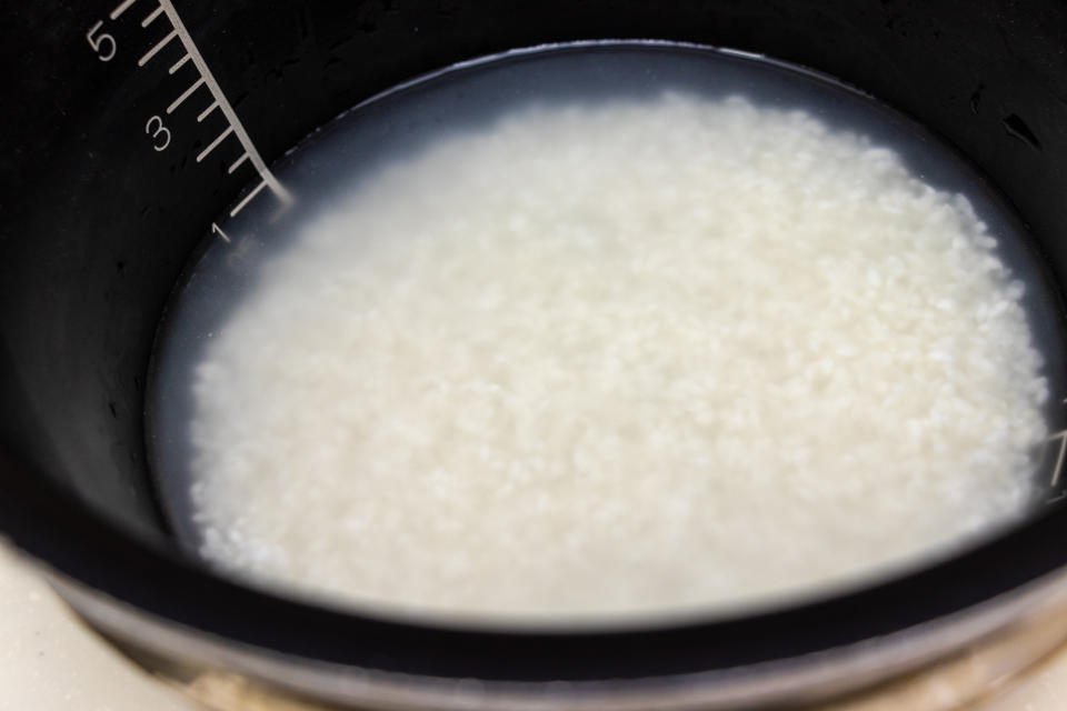rice in a rice cooker covered in cloudy water