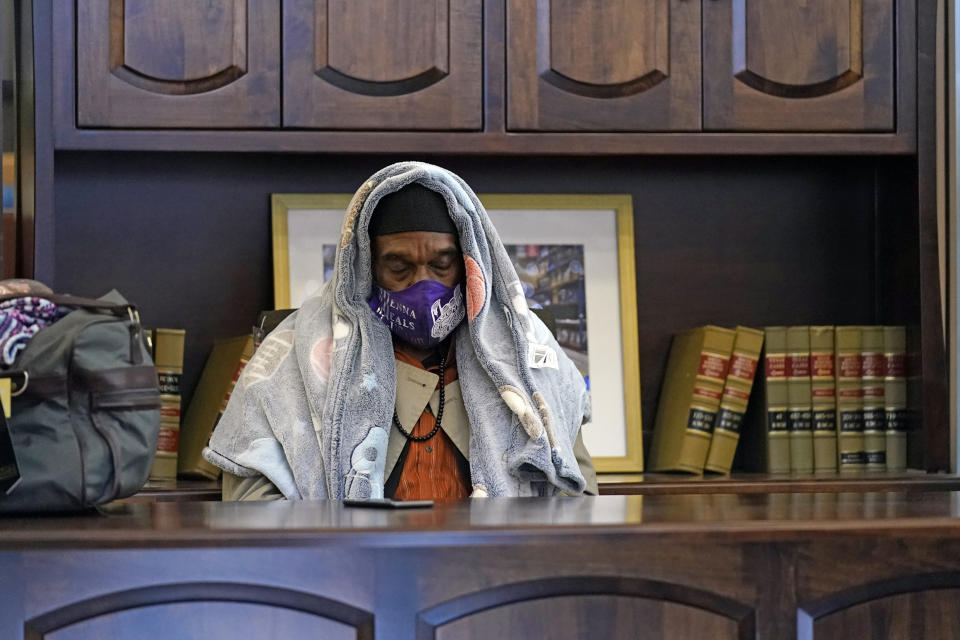 Michael Singletary rests behind a desk at a Gallery Furniture store which opened as a shelter for those without power Wednesday, Feb. 17, 2021, in Houston. Millions in Texas still had no power after a historic snowfall and single-digit temperatures created a surge of demand for electricity to warm up homes unaccustomed to such extreme lows, buckling the state's power grid and causing widespread blackouts. (AP Photo/David J. Phillip)