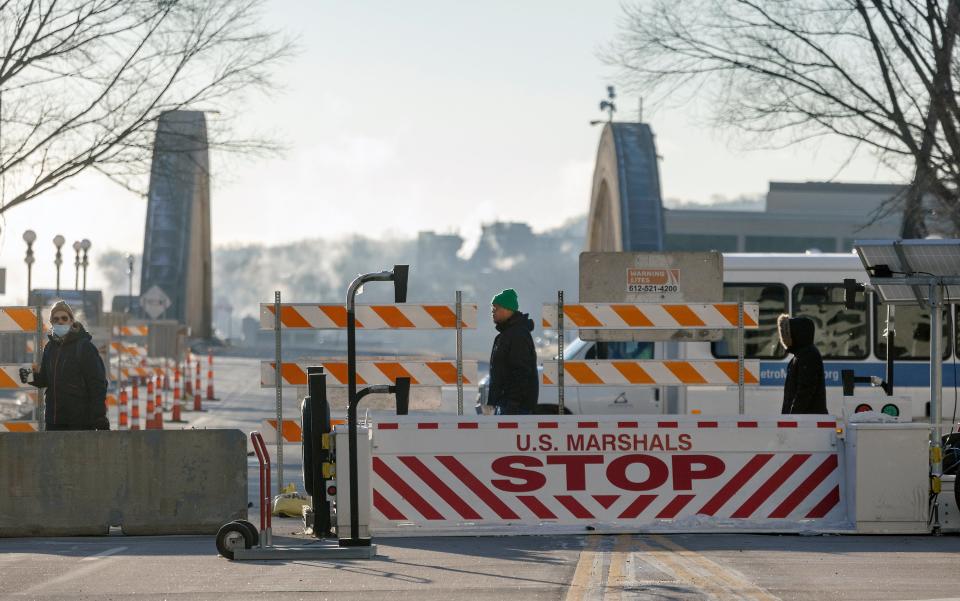 Pedestrians made their way across a closed street near the heavily gated Warren E. Burger Federal Building on Thursday (AP)