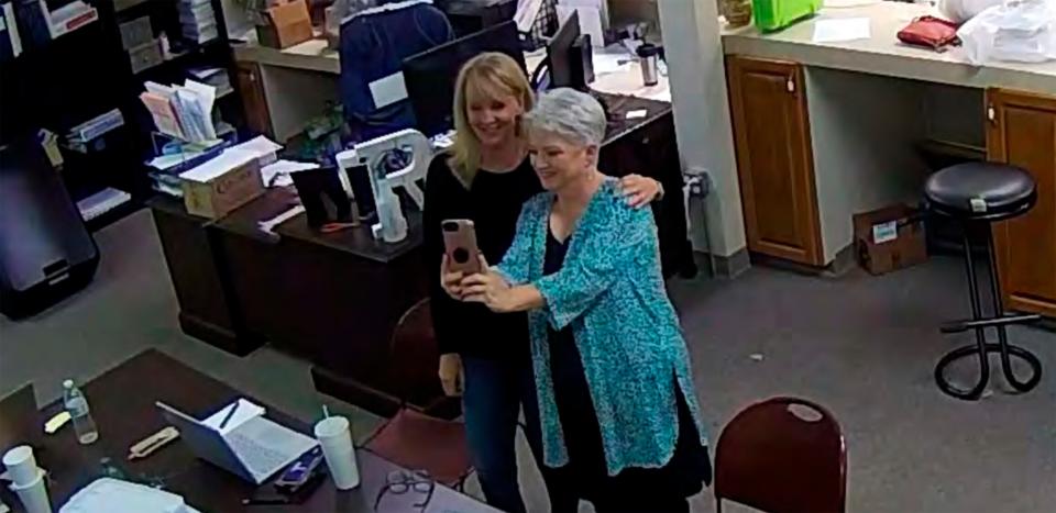 In this Jan. 7, 2021, image taken from Coffee County, Ga., security video, Cathy Latham, right, appears to take a selfie with a member of a computer forensics team inside the local elections office. Latham was the county Republican Party chair at the time. The computer forensics team was at the county elections office in Douglas, Ga., to make copies of voting equipment in an effort that documents show was arranged by attorney Sidney Powell and others allied with then-President Donald Trump.