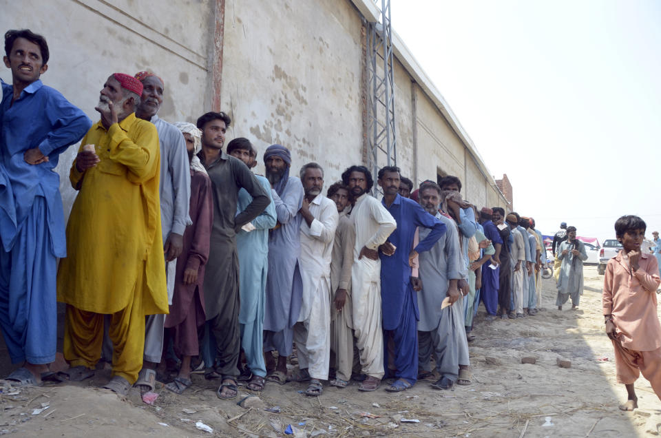 Displaced families, who fled their flood-hit homes, line up to get relief aid in Jaffarabad, a district of Baluchistan province, Pakistan, Wednesday, Sept. 21, 2022. Devastating floods in Pakistan's worst-hit province have killed 10 more people in the past day, including four children, officials said Wednesday as the U.N. children's agency renewed its appeal for $39 million to help the most vulnerable flood victims. (AP Photo/Zahid Hussain)