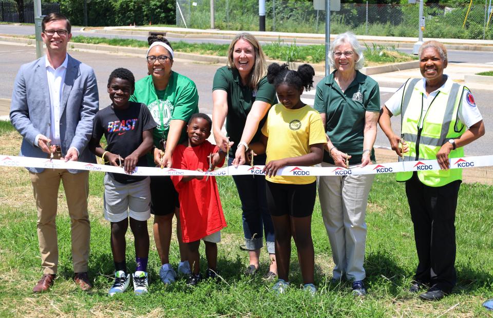 Bike Walk Knoxville and Knoxville’s Community Development Corporation (KCDC) officially open a signalized crosswalk linking Green Magnet Academy and the First Creek at Austin housing development May 19. Ceremony participants included: front row, from left: Green Magnet Academy students Jeremiah Mingo, Jonathan Everhart and Denaysha Echols; back row, from left: Ben Bentley of KCDC; Jessica Holman of Green Magnet Academy; Lindsey Kimble and Caroline Cooley of Bike Walk Knoxville; and crossing guard Karen Moon.