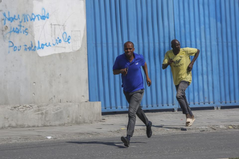 Pedestrians run for cover after hearing gunshots, in Port-au-Prince, Haiti, Wednesday, March 13, 2024. (AP Photo/Odelyn Joseph)