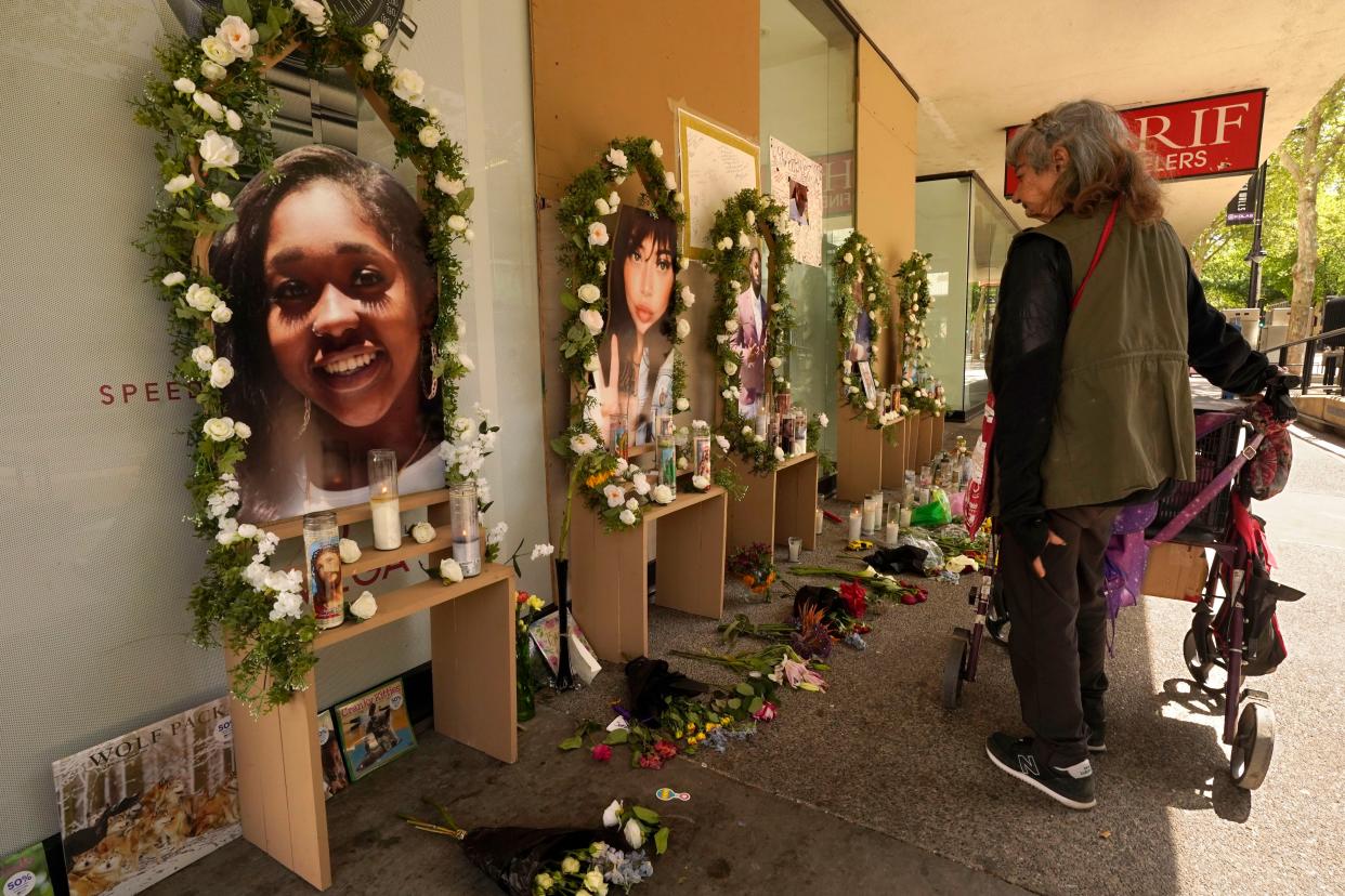 A passerby pauses at a memorial for the people killed in mass shooting in Sacramento, Calif., April 6, 2022. 