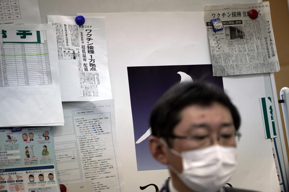 Newspapers' clips on COVID-19 vaccination are posted on a board as Hitoshi Iwase, head of the local office for COVID-19 vaccination preparation at Tokyo's Sumida ward office works Friday, Jan. 22, 2021. Japan is accelerating preparations for COVID-19 vaccinations in hopes of starting them in late February, but uncertainty is growing as the country faces vaccine-shy public, slow approval process and bureaucratic roadblocks, casting a doubt if Tokyo Olympic this summer is possible. (AP Photo/Eugene Hoshiko)