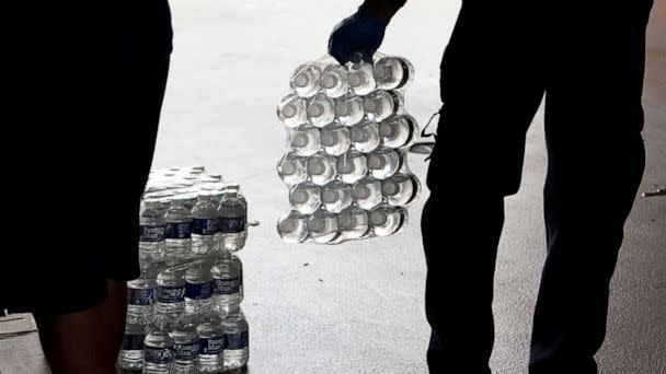 PHOTO: Bottled water is carried to a residents car by a recruit at the Fire Department in Jackson, Miss., Aug. 18, 2022.  (Rogelio V. Solis/AP)