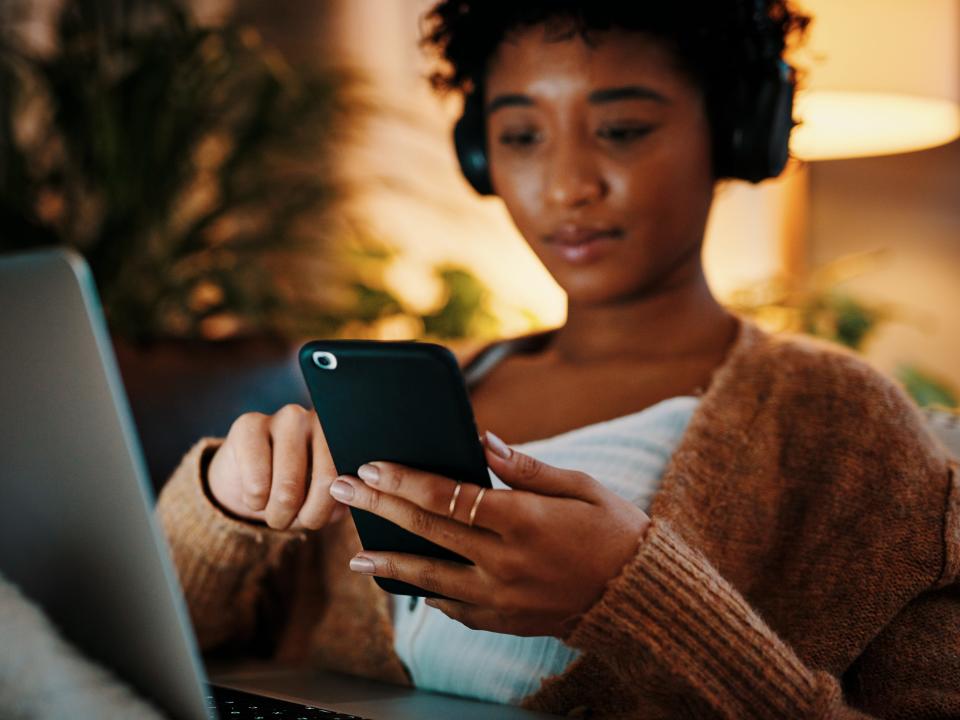 woman on laptop and phone wearing headphones