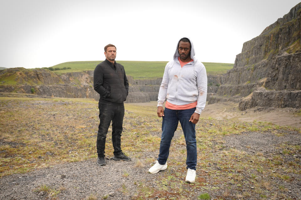 Warren and Felix standing by a cliff.