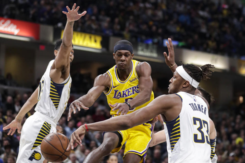 Los Angeles Lakers guard Rajon Rondo (9) loose the ball as he cuts between Indiana Pacers center Myles Turner (33) and guard Jeremy Lamb (26) during the first half of an NBA basketball game in Indianapolis, Tuesday, Dec. 17, 2019. (AP Photo/Michael Conroy)