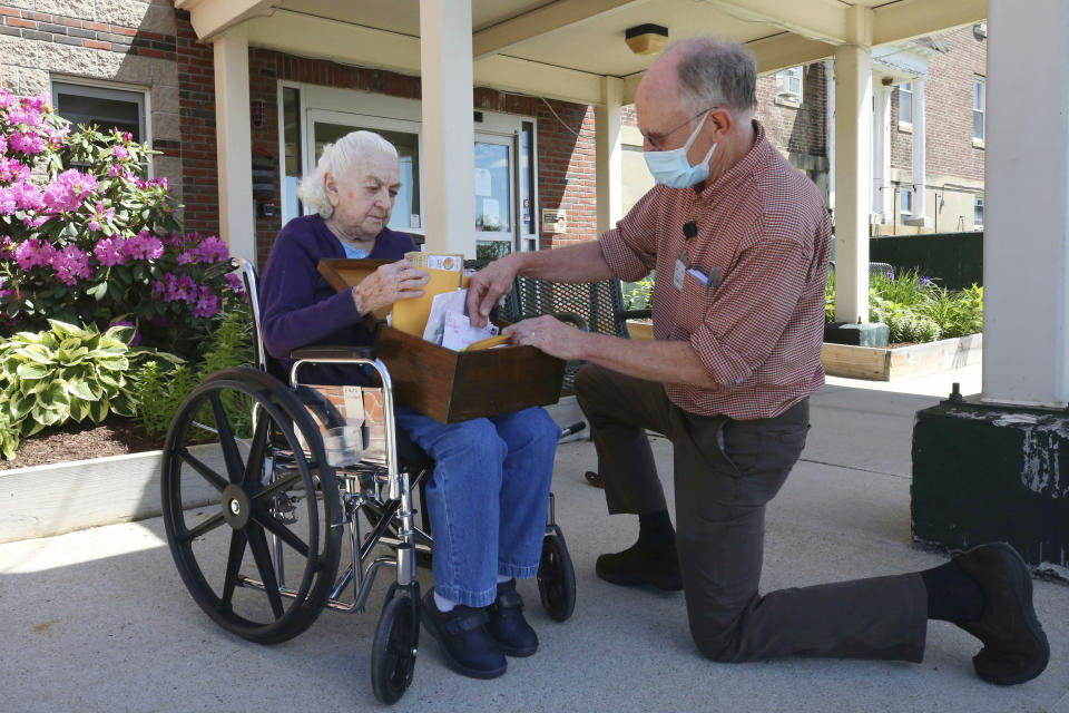 In this Monday, June 8, 2020, photo, 93-year-old Flo Young, originally from Cambridge, Mass., browses through pen pal letters with activity aide Rich Vanderweit, right, outside the Sullivan County Health Care nursing home in Unity, N.H. In a letter-writing effort during the virus pandemic to connect nursing home residents in two neighboring communities, residents now are receiving pen pal letters from across the United States. (AP Photo/Charles Krupa)