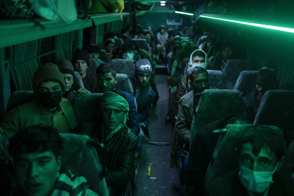 Afghan men sit in a bus in Herat, Afghanistan, Monday , Nov. 22, 2021, for a 300-mile trip south to Nimrooz near the Iranian border. Afghans are streaming across the border into Iran, driven by desperation after the near collapse of their country's economy following the Taliban's takeover in mid-August. In the past three months, more than 300,000 people have crossed illegally into Iran, according to the Norwegian Refugee Council, and more are coming at the rate of 4,000 to 5,000 a day. (AP Photo/Petros Giannakouris)
