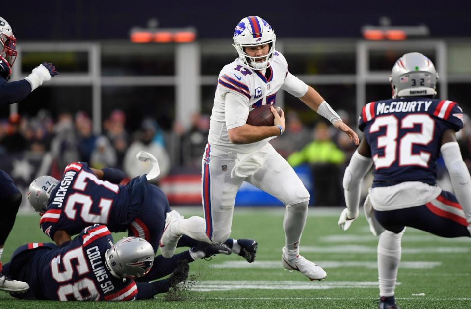 Buffalo Bills quarterback Josh Allen (17) runs with the ball while evading tackles by New England Patriots cornerback J.C. Jackson (27) and inside linebacker Jamie Collins (58) during the second half at Gillette Stadium.