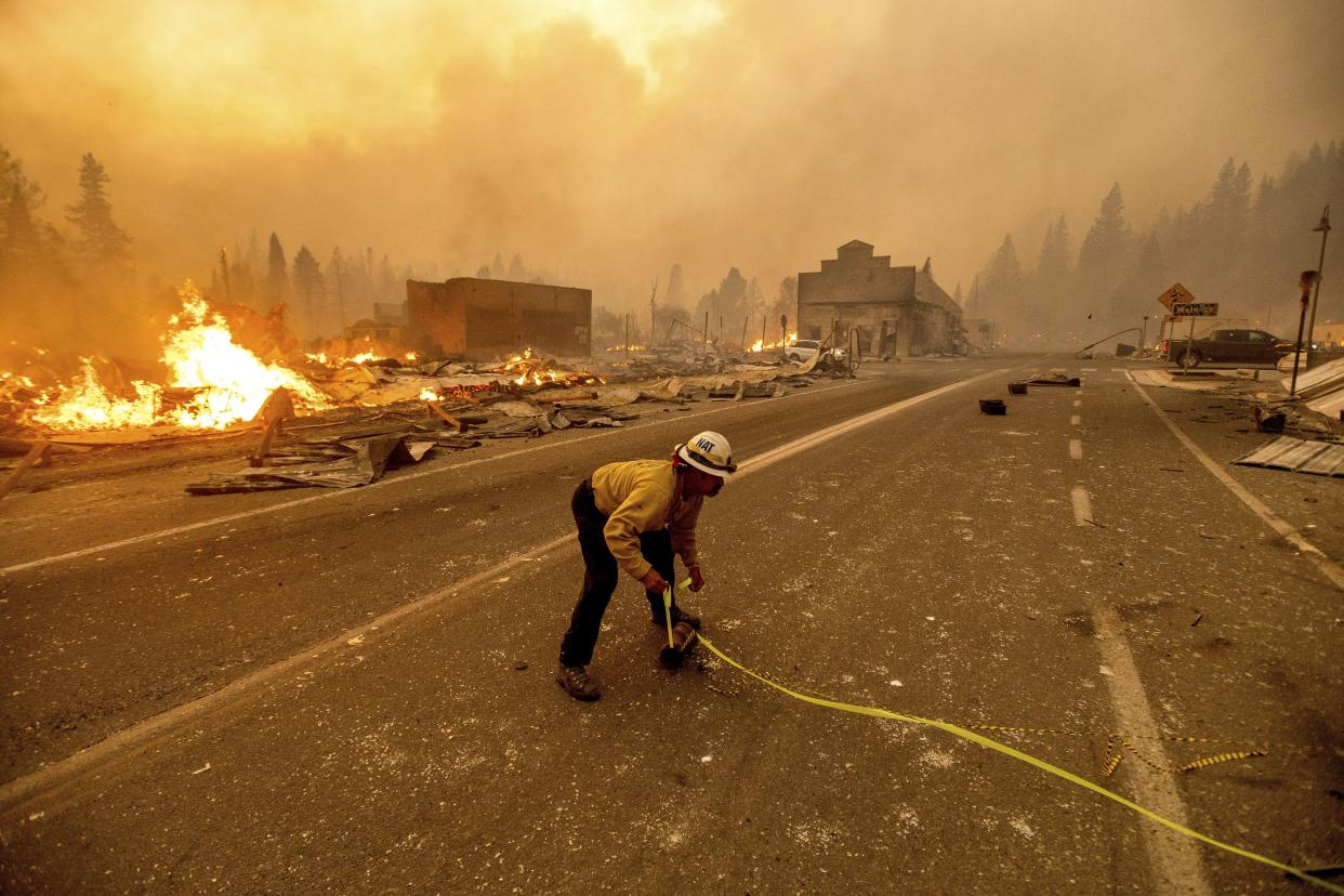 Battalion Chief Sergio Mora marks a road hazard as the Dixie Fire tears through the Greenville community of Plumas County, Calif. on Wednesday, Aug. 4, 2021. The fire leveled multiple historic buildings and dozens of homes in central Greenville.