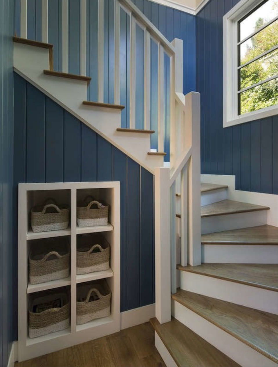 winding staircase with blue walls and small cubby holes in wall with baskets for storage