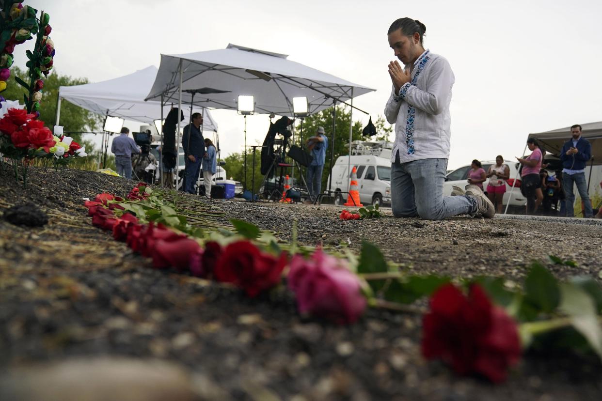 Carlow Eduardo Espina prays after placing roses on a make-shift memorial at the site where officials found dozens of people dead in a semitrailer containing suspected migrants on Tuesday, June 28, 2022, in San Antonio.