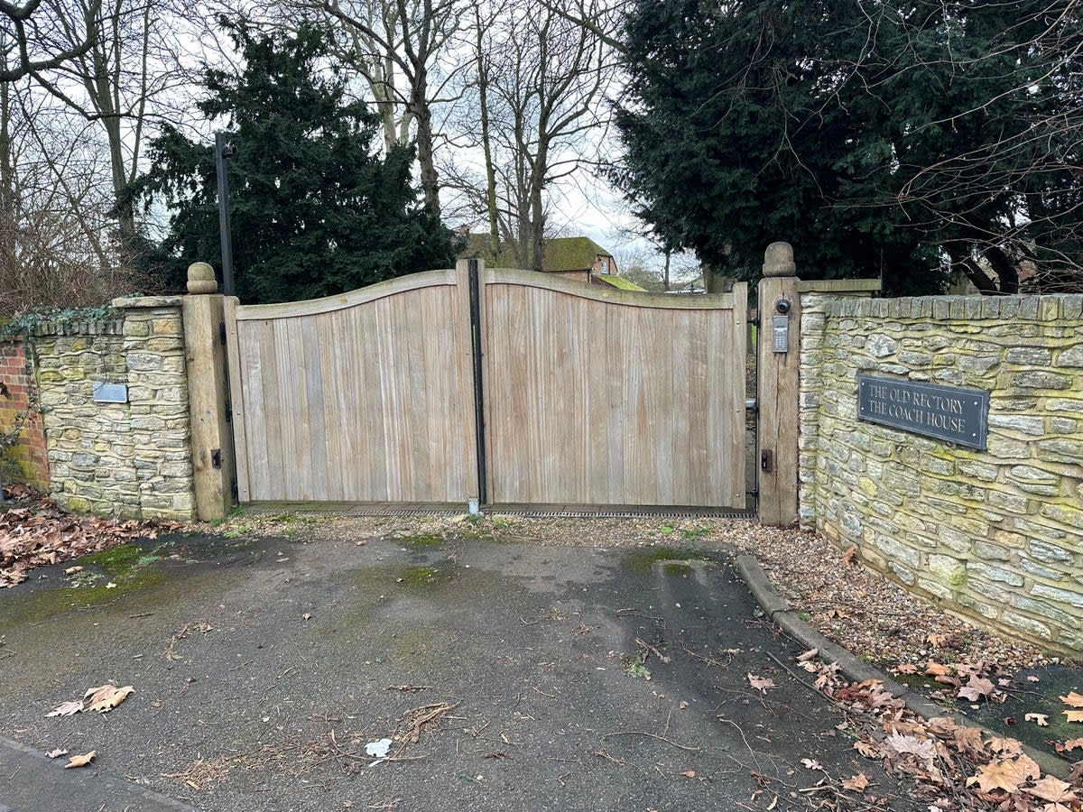 The gated entrance to The Old Rectory. Fencing and trees surround the boundary to the house and garden (The Independent)